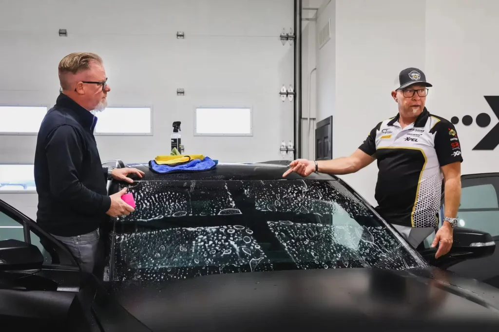 Professional installer applying PPF installation gel to car panel during paint protection film installation