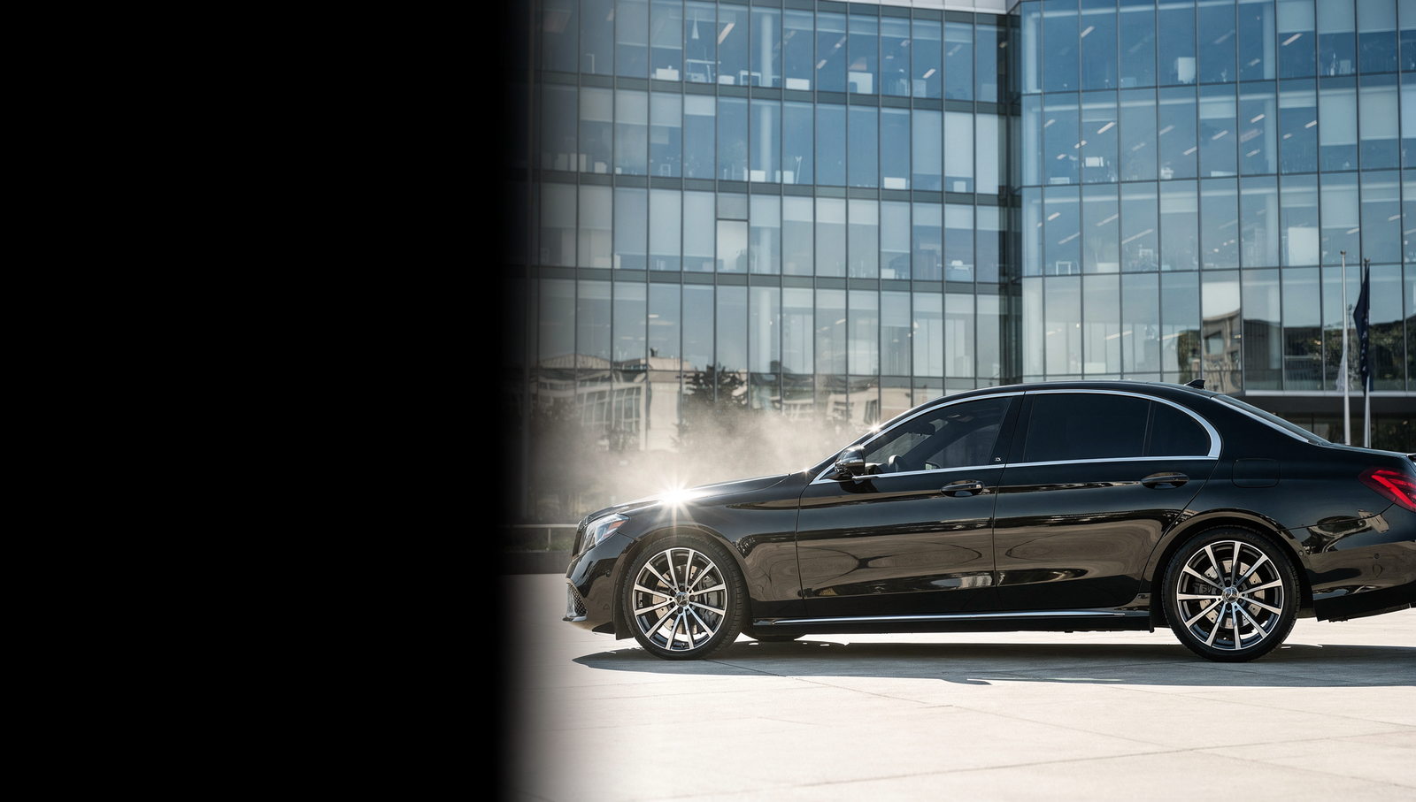 Luxury black sedan with dark ceramic window tint in bright sunlight